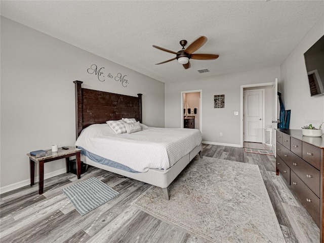 bedroom featuring ceiling fan, ensuite bathroom, a textured ceiling, and light hardwood / wood-style flooring