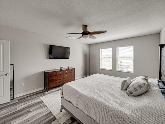 bedroom with a textured ceiling, ceiling fan, and light wood-type flooring