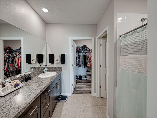 bathroom featuring a shower with shower curtain, tile patterned flooring, a textured ceiling, and vanity