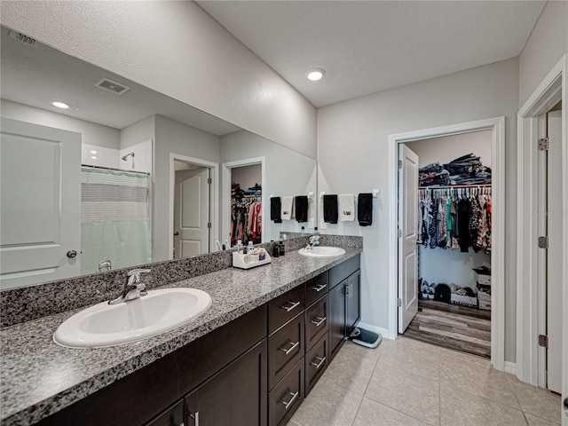 bathroom with a textured ceiling, vanity, tile patterned floors, and walk in shower