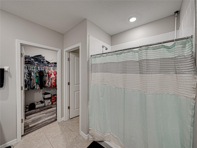 bathroom featuring tile patterned flooring, walk in shower, and a textured ceiling