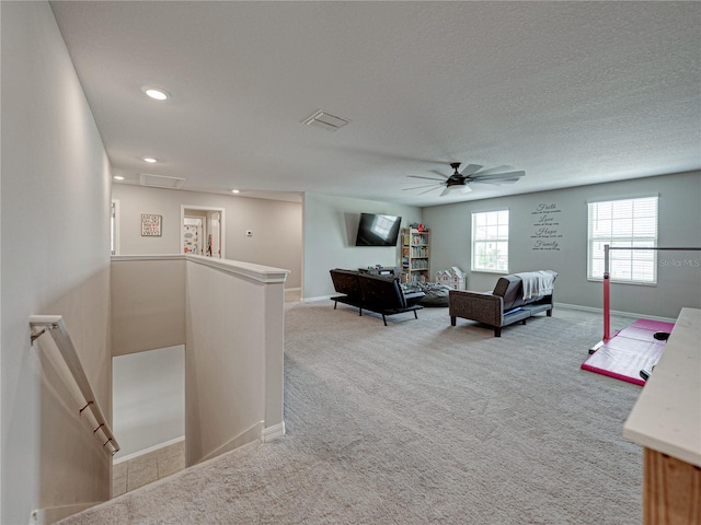 living room with ceiling fan, a textured ceiling, and carpet floors