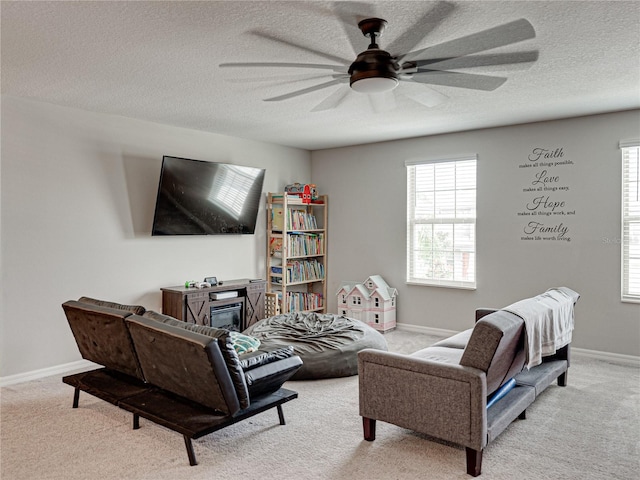 carpeted living room with a textured ceiling, plenty of natural light, and ceiling fan