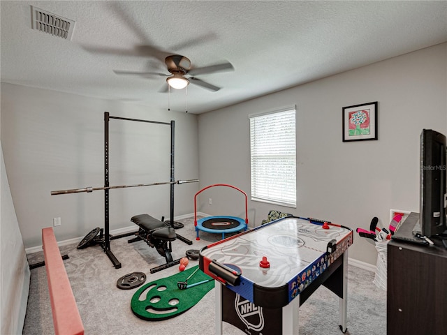 recreation room featuring a textured ceiling, light colored carpet, and ceiling fan