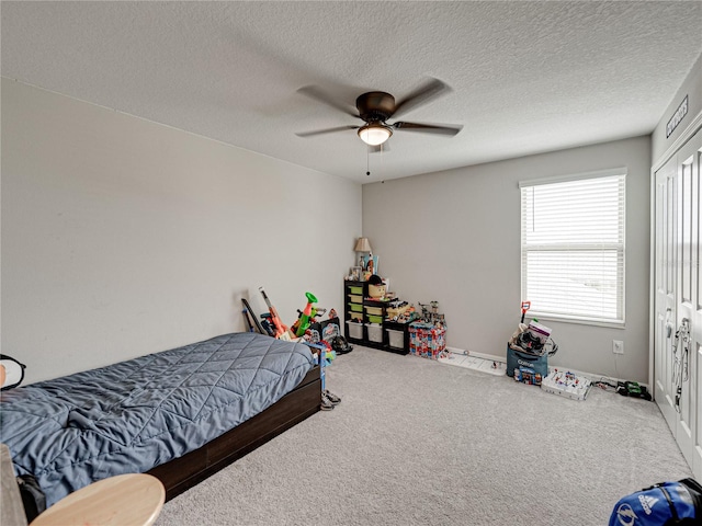 carpeted bedroom featuring ceiling fan and a textured ceiling