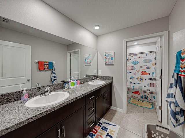 bathroom with a textured ceiling, vanity, curtained shower, and tile patterned flooring