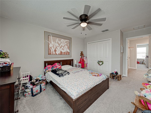 carpeted bedroom with a textured ceiling, ceiling fan, and a closet