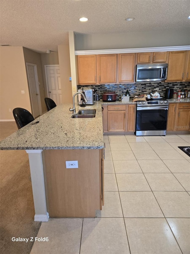 kitchen featuring a kitchen breakfast bar, light stone counters, kitchen peninsula, sink, and appliances with stainless steel finishes