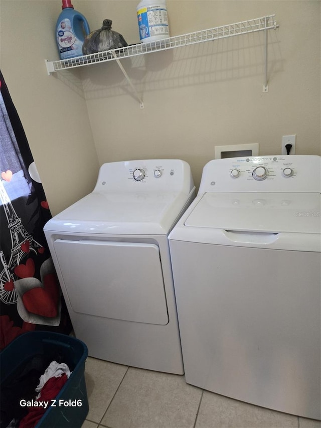 laundry area with light tile patterned floors and washer and clothes dryer