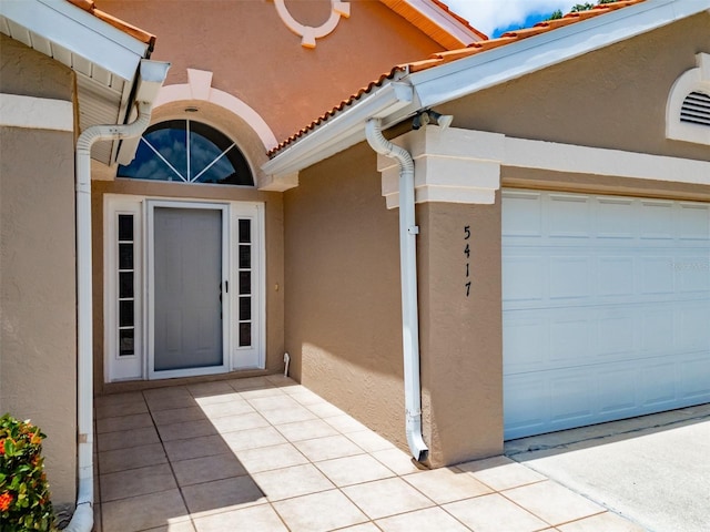 entrance to property with a tile roof and stucco siding