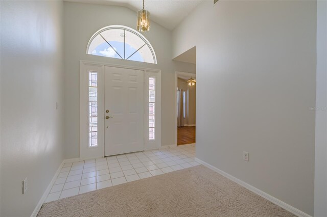 entrance foyer featuring light carpet, vaulted ceiling, and ceiling fan with notable chandelier