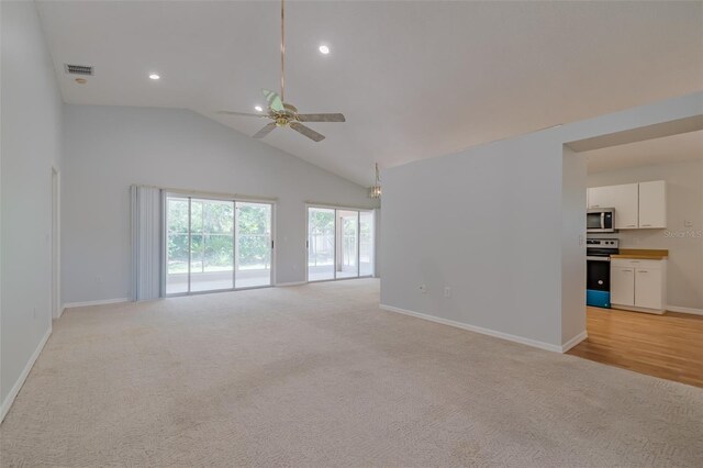 unfurnished living room with high vaulted ceiling, ceiling fan, and light carpet