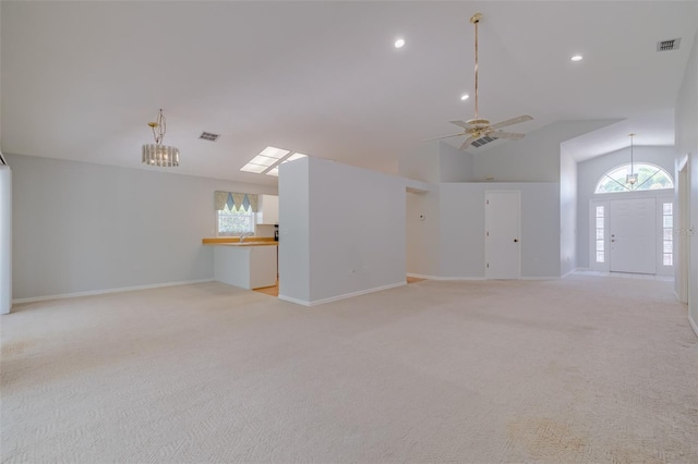 unfurnished living room featuring lofted ceiling, ceiling fan with notable chandelier, and light carpet