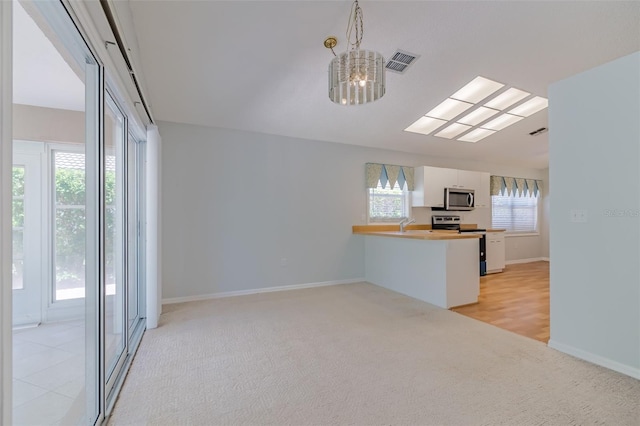 kitchen with a wealth of natural light, stainless steel appliances, kitchen peninsula, and white cabinets