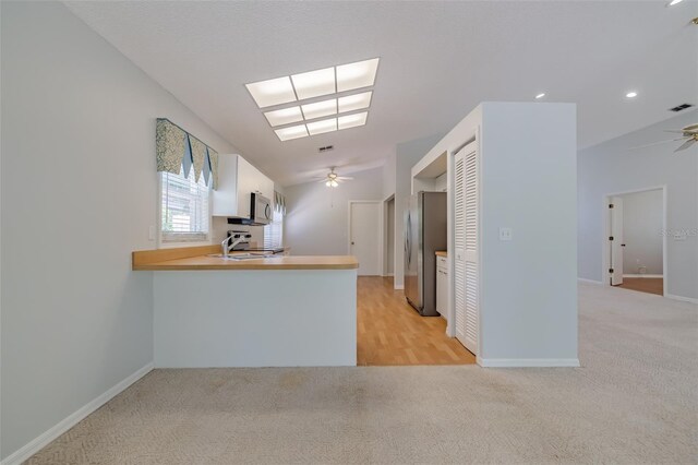 kitchen with lofted ceiling, ceiling fan, light carpet, and appliances with stainless steel finishes