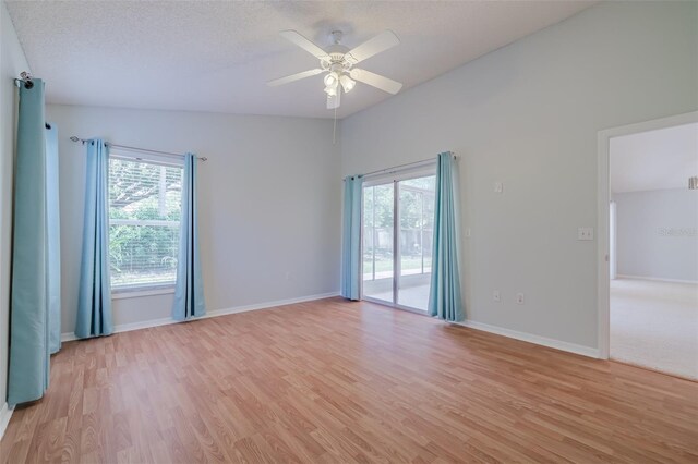 spare room featuring a textured ceiling, light hardwood / wood-style flooring, ceiling fan, and lofted ceiling