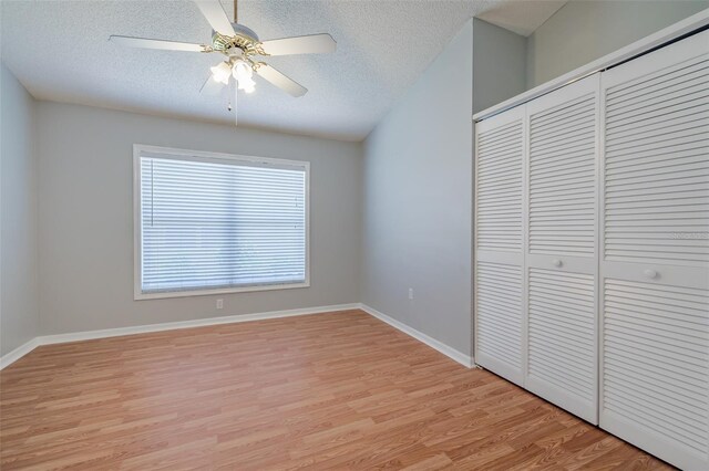 unfurnished bedroom featuring light wood-type flooring, a textured ceiling, ceiling fan, and a closet