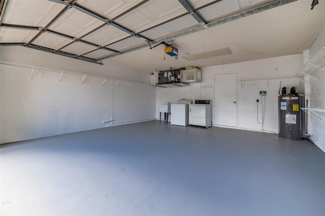 garage featuring electric water heater, independent washer and dryer, and a garage door opener