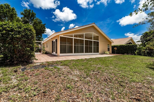 rear view of property featuring a sunroom, a lawn, and a patio