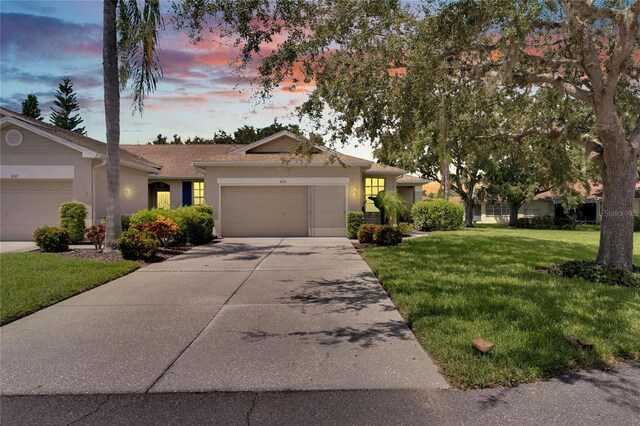 ranch-style home with a garage and a lawn