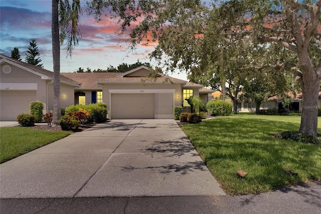 ranch-style home with an attached garage, driveway, a lawn, and stucco siding