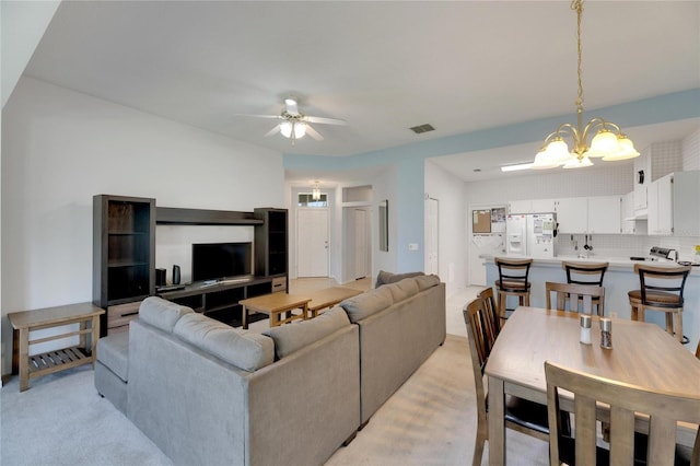 carpeted living room featuring ceiling fan with notable chandelier