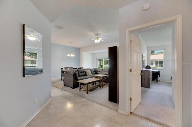 corridor with a textured ceiling and light colored carpet