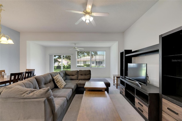 living room featuring ceiling fan with notable chandelier, a textured ceiling, and carpet floors