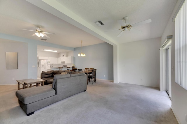 living room featuring ceiling fan with notable chandelier, a textured ceiling, and light colored carpet