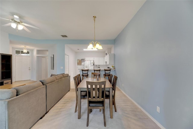 carpeted dining area with ceiling fan with notable chandelier