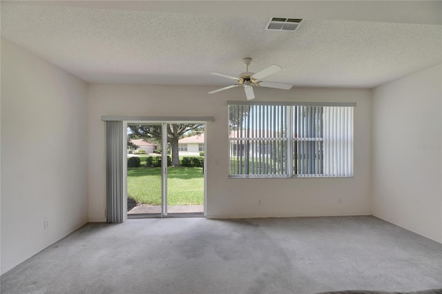 empty room with light colored carpet, ceiling fan, and a textured ceiling