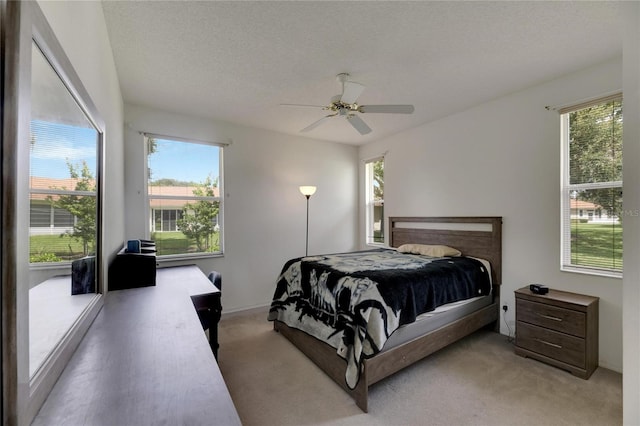 carpeted bedroom with multiple windows, a textured ceiling, and ceiling fan