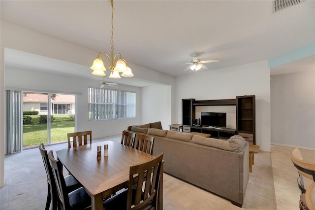 carpeted dining space featuring ceiling fan with notable chandelier