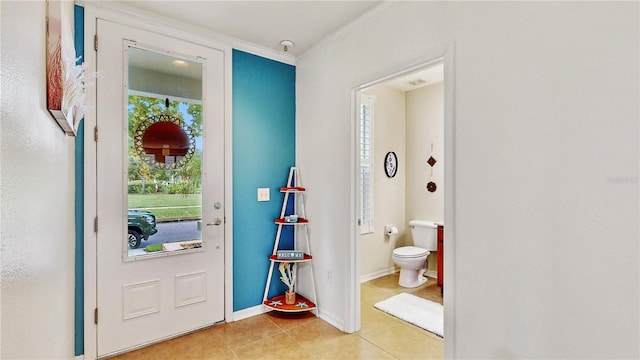 foyer with light tile patterned floors and crown molding