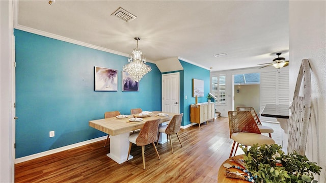 dining area featuring ceiling fan with notable chandelier, ornamental molding, and wood-type flooring