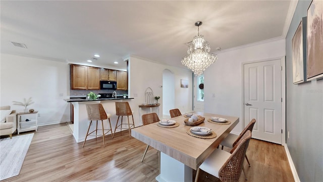 dining room with crown molding, a notable chandelier, and light wood-type flooring