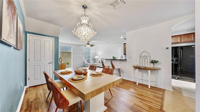 dining space with light wood-type flooring and ceiling fan with notable chandelier