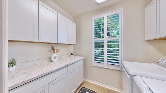 clothes washing area featuring light tile patterned floors, cabinets, and washing machine and dryer