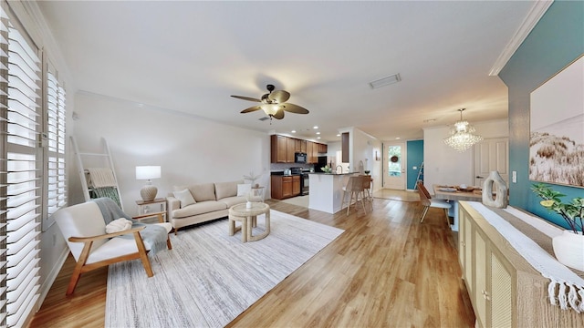 living room featuring crown molding, light hardwood / wood-style flooring, and ceiling fan with notable chandelier