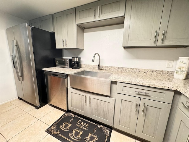 kitchen featuring light tile patterned floors, appliances with stainless steel finishes, light stone countertops, sink, and gray cabinets