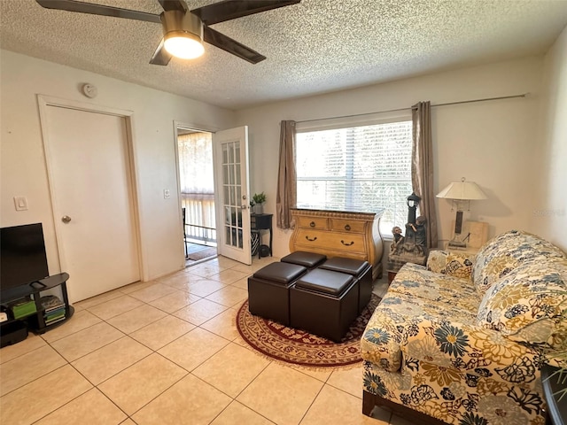 living room with ceiling fan, light tile patterned floors, and a textured ceiling