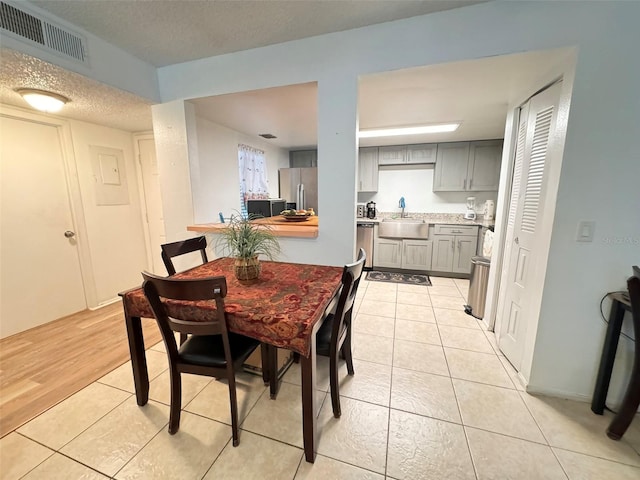 dining space with a textured ceiling, sink, and light hardwood / wood-style floors