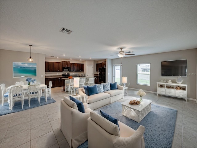 tiled living room with ceiling fan and a textured ceiling