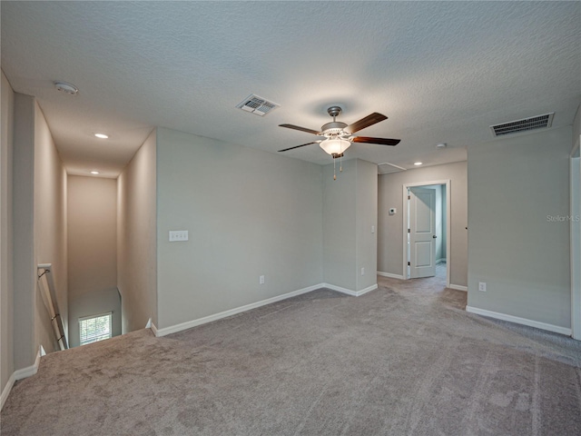 carpeted spare room featuring ceiling fan and a textured ceiling