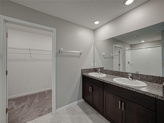 bathroom featuring a textured ceiling, walk in shower, and vanity