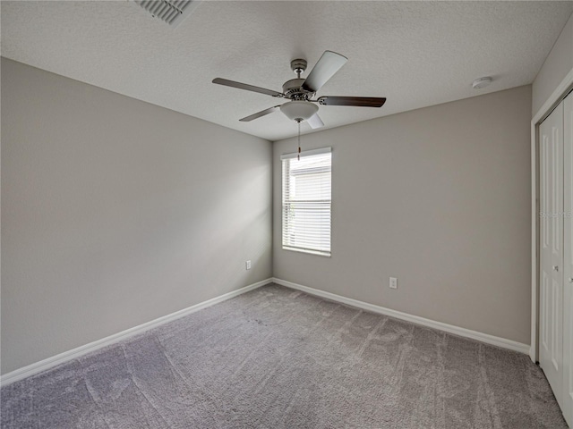 spare room featuring a textured ceiling, ceiling fan, and carpet