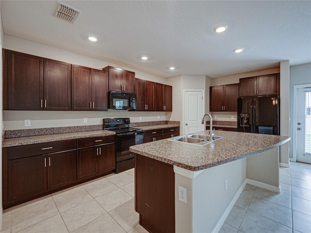 kitchen featuring light tile patterned floors, sink, a kitchen island with sink, and black appliances