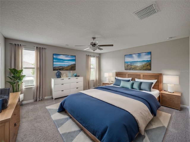 bedroom featuring a textured ceiling, ceiling fan, and light colored carpet