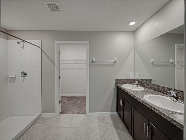 bathroom with vanity, tile patterned floors, a textured ceiling, and a tile shower