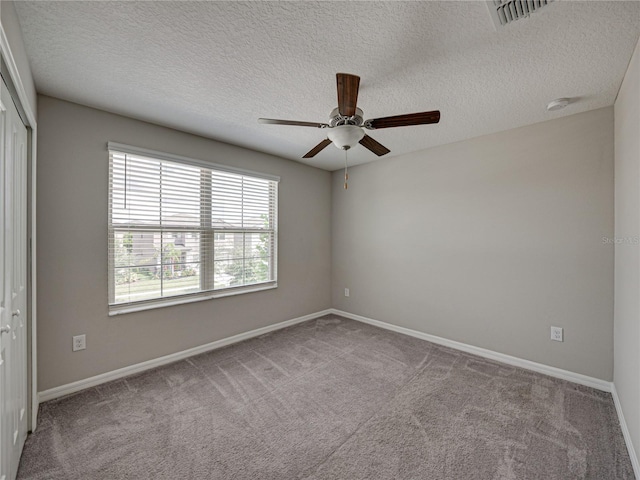 carpeted spare room featuring ceiling fan and a textured ceiling